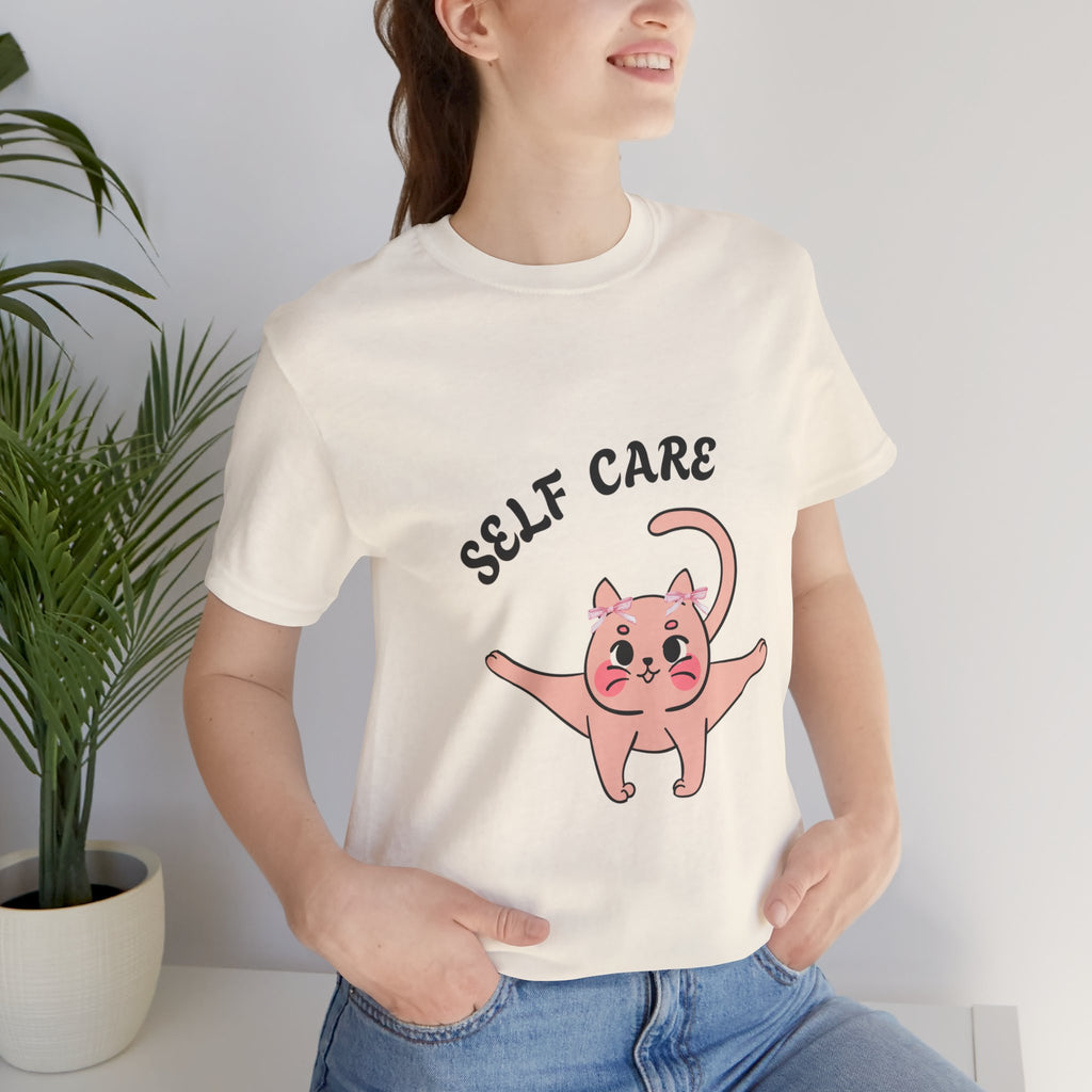 Person wearing a Natural t-shirt with a pink cat illustration and 'SELF CARE' text.