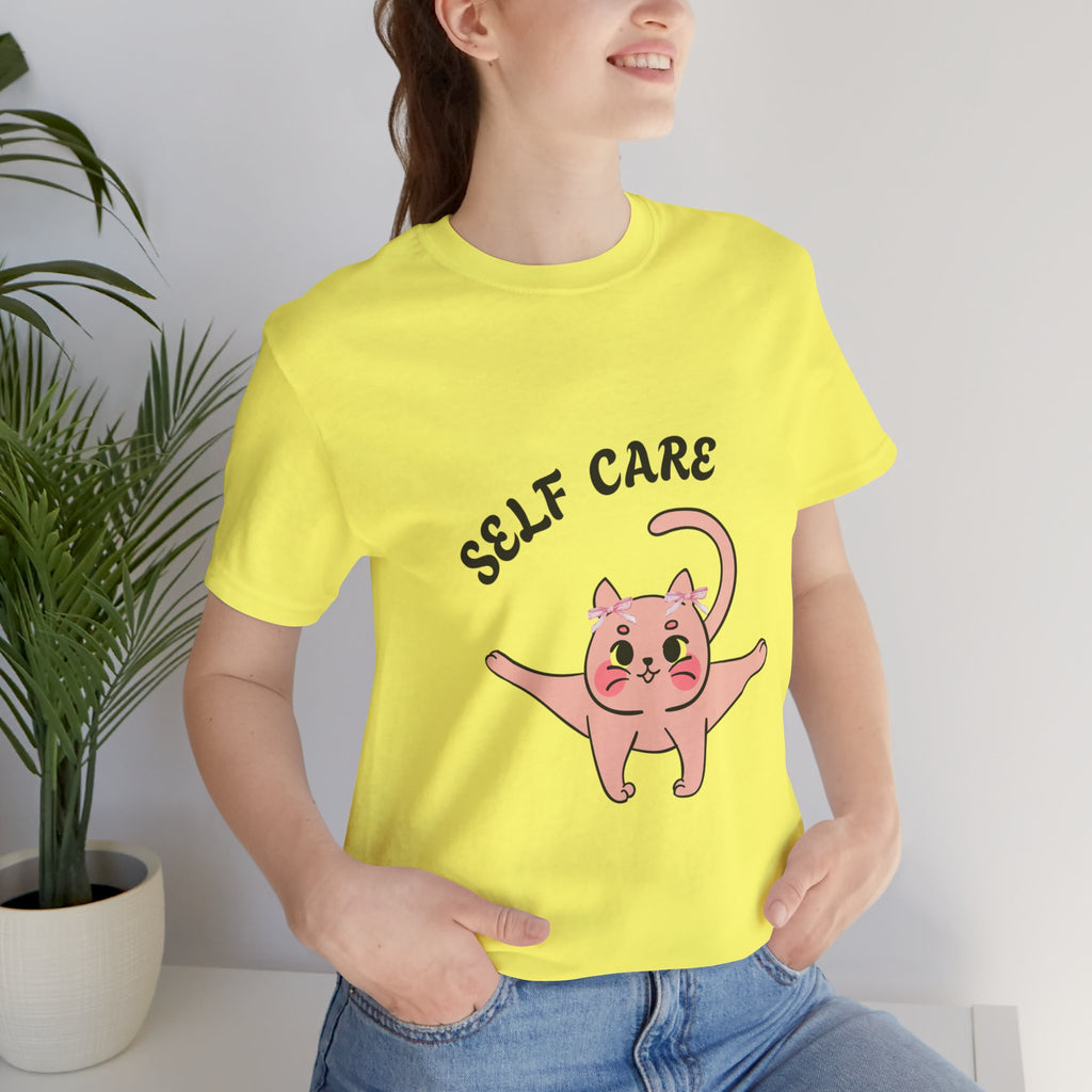 Person wearing a yellow t-shirt with a pink cat illustration and 'SELF CARE' text.