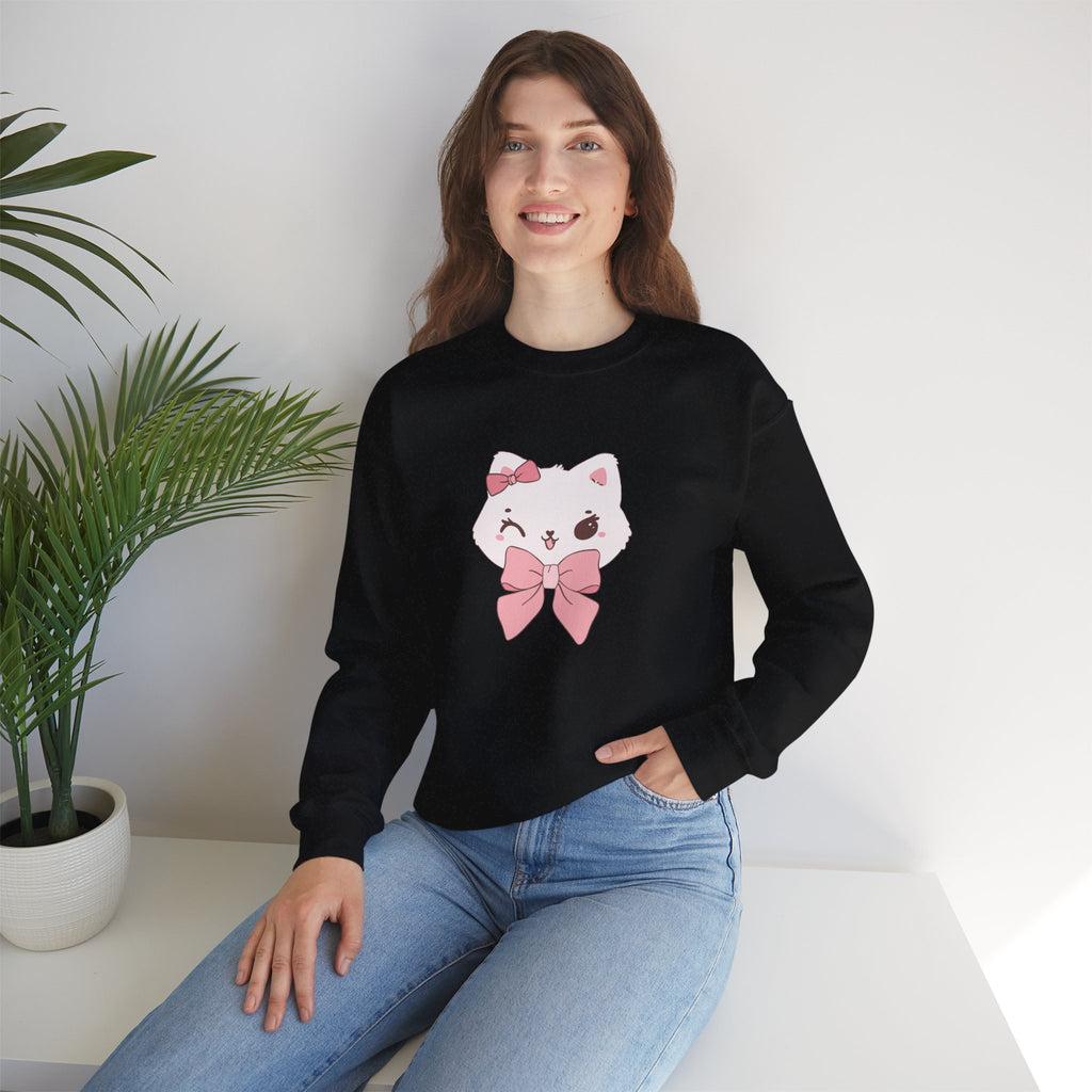 Woman wearing a black sweatshirt with a white cat design and pink bow, sitting on a white surface with a plant in the background.