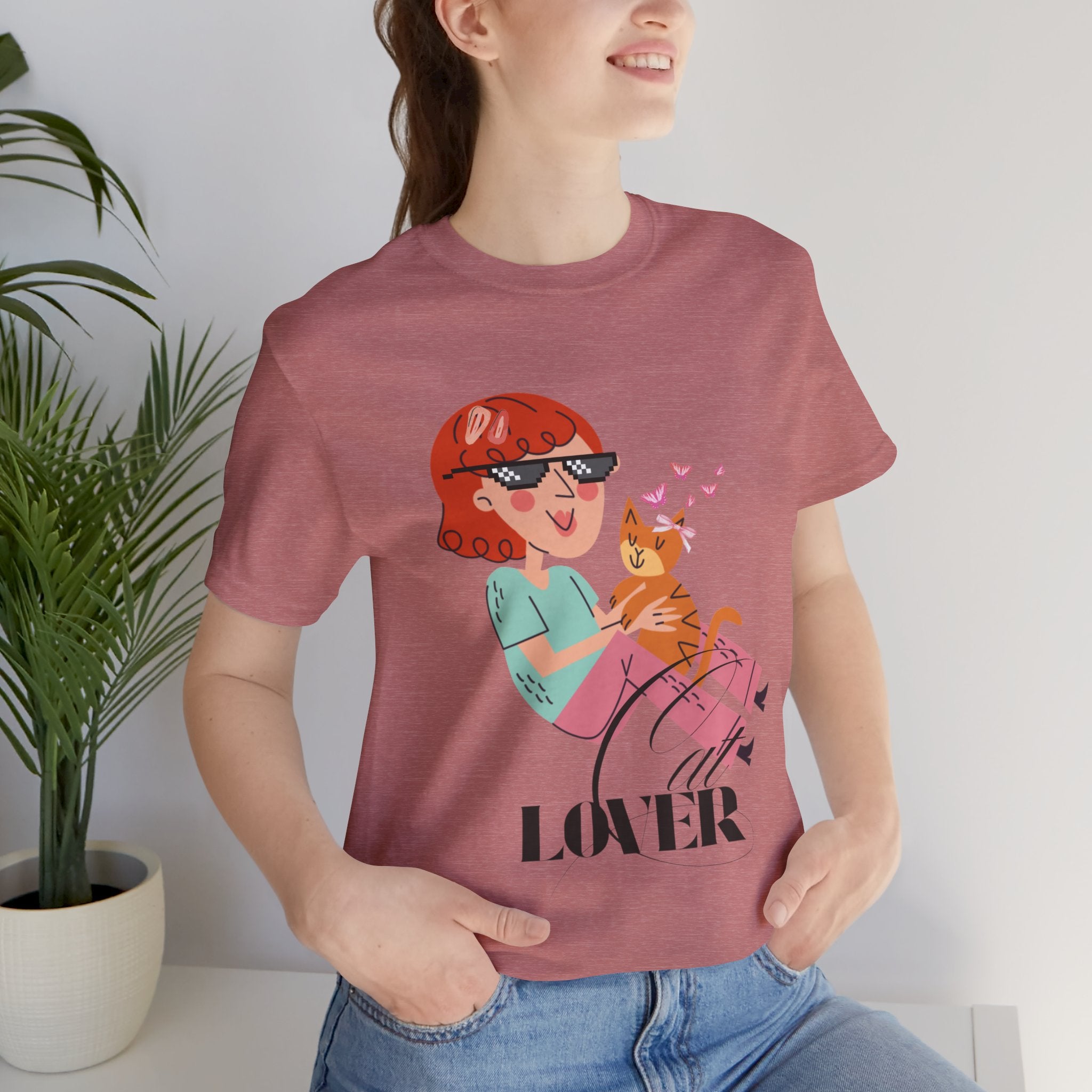 Person wearing a Heather Mauve t-shirt with a graphic design of a girl holding a cat and the word 'Cat LOVER'.
