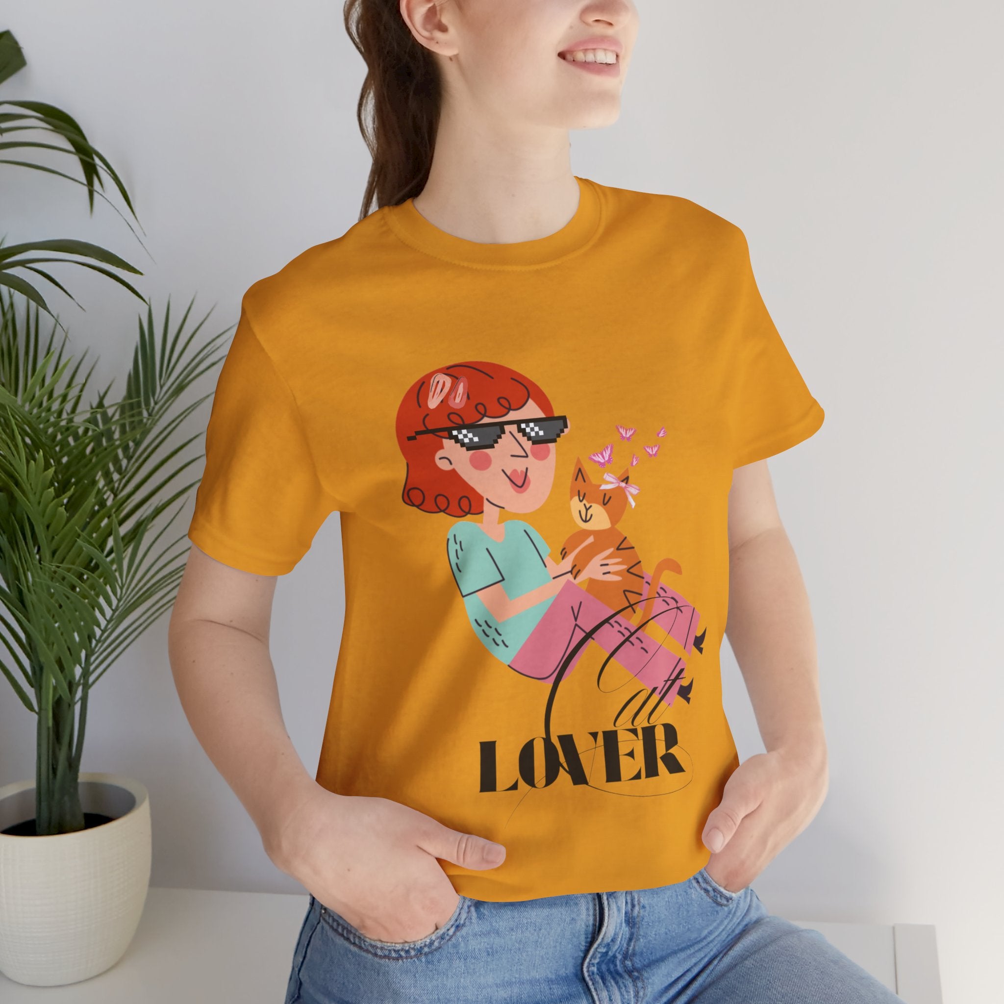 Person wearing a mustard t-shirt with a graphic design and the word 'Cat LOVER'.