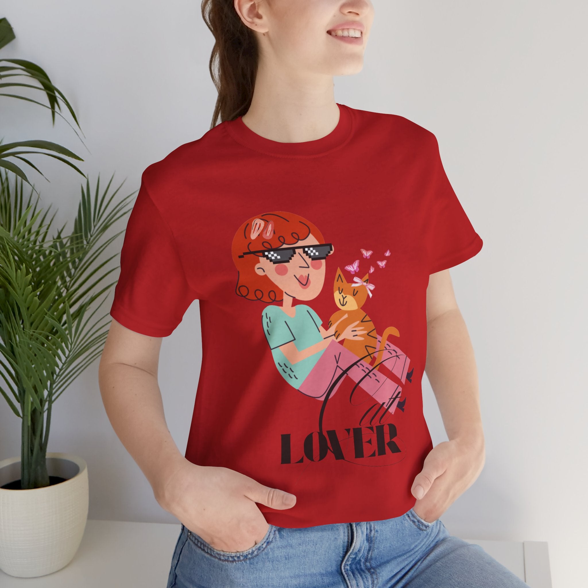 Person wearing a red t-shirt with a graphic design and the word 'Cat LOVER' sitting indoors.