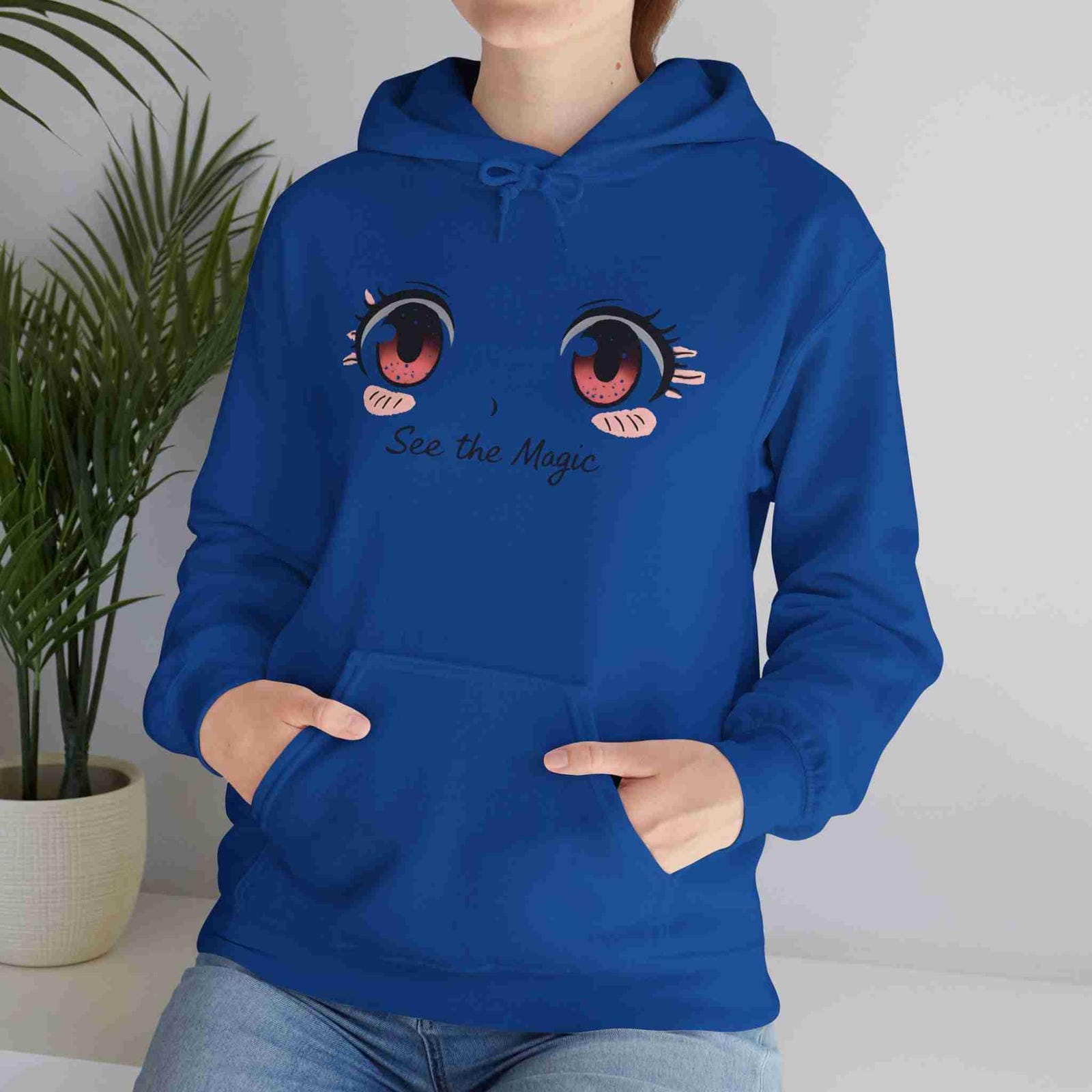 Person wearing a Royal hoodie with cartoon eyes and 'See the Magic' text, standing indoors.