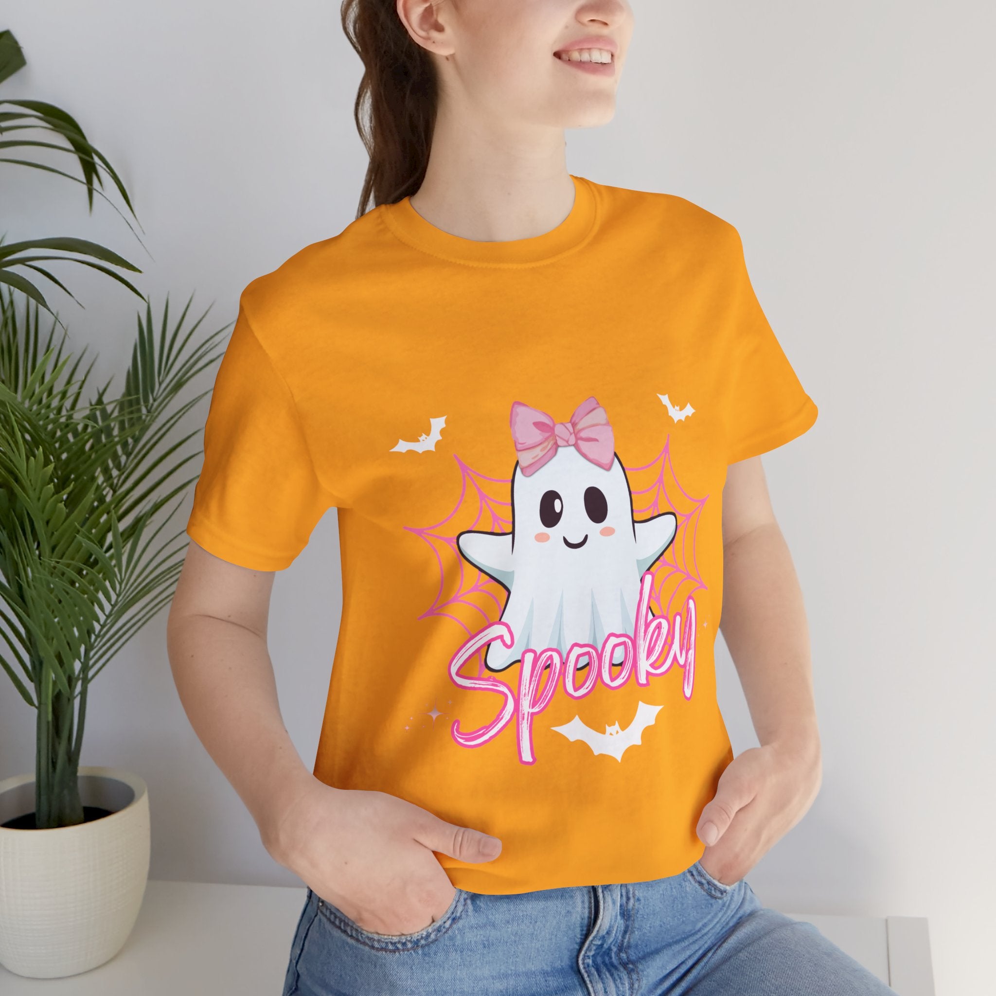 Person wearing a Gold t-shirt with a ghost graphic and 'Spooky' text, standing indoors.