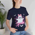 Person wearing a navy t-shirt with a ghost design and 'Spooky' text, standing indoors.