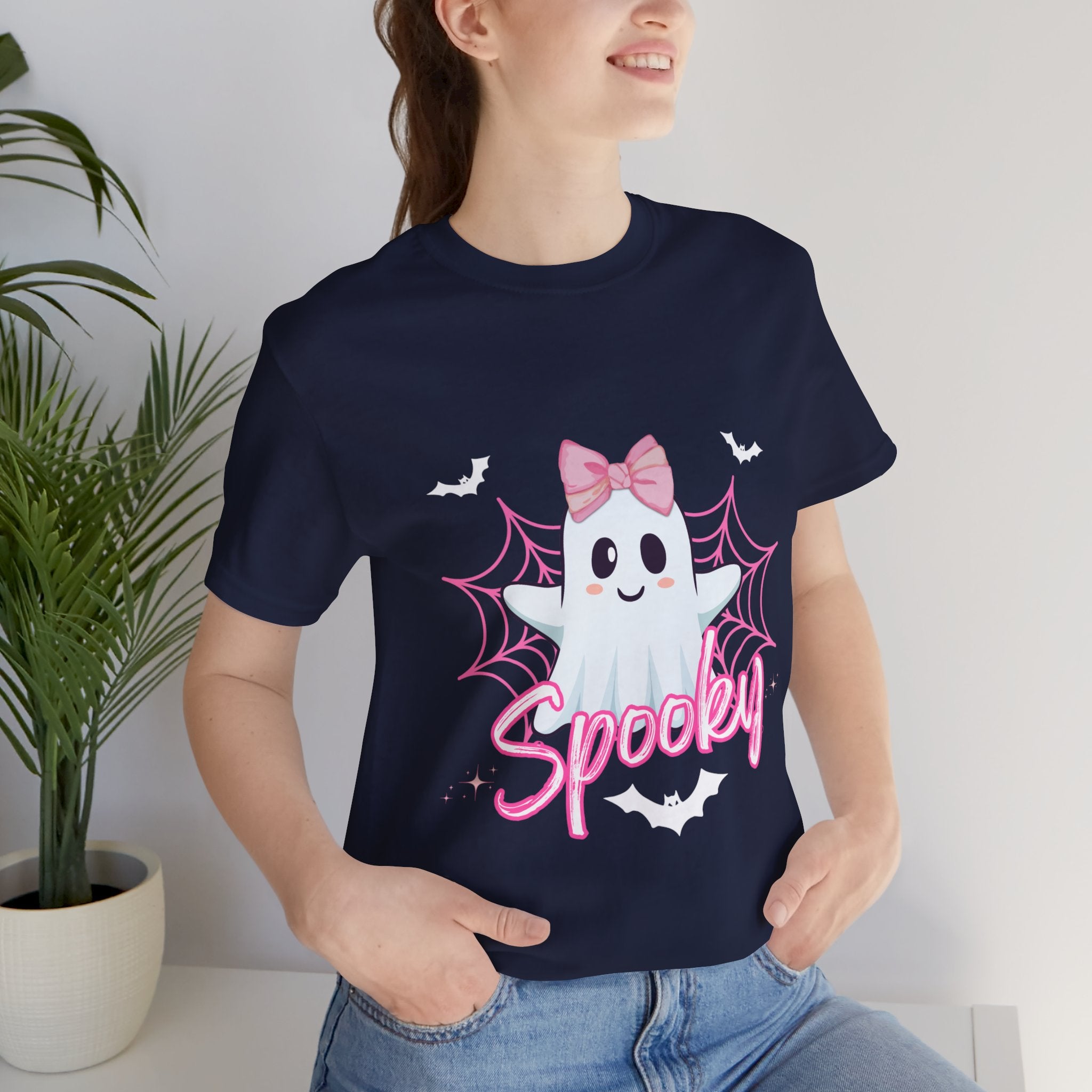 Person wearing a navy t-shirt with a ghost design and 'Spooky' text, standing indoors.