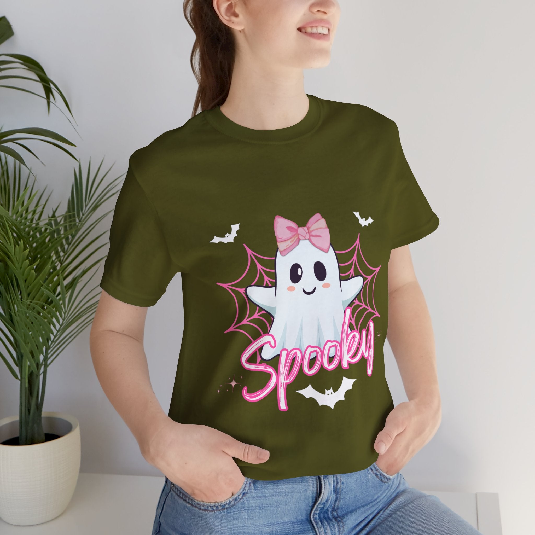 Person wearing a Olive t-shirt with a ghost design and 'Spooky' text, standing indoors.